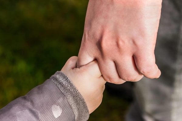 Barnehånd holder finger på voksenhånd