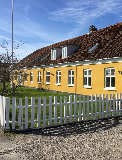 Gult pudset hus med hvide vinduer