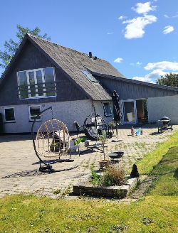 Hus med 1. sal og lille anneks, set fra haven med fliseterrasse