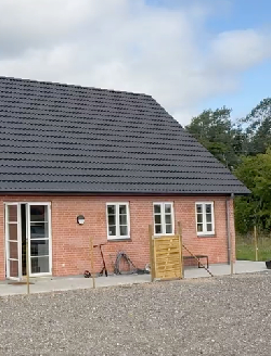 Rødt murtenshus med hvide vinduer og døre. Nyt sort tag